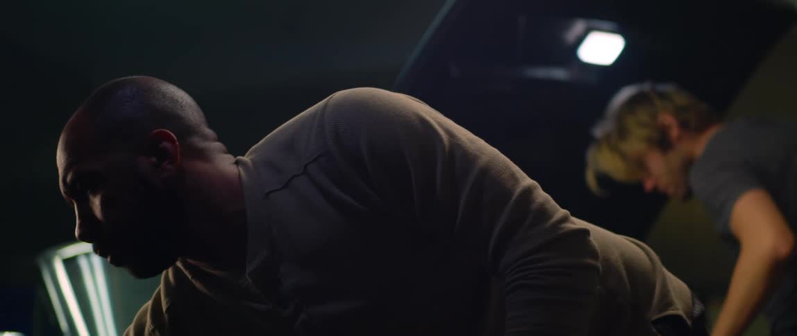 Two mechanics work on separate vehicles in a garage