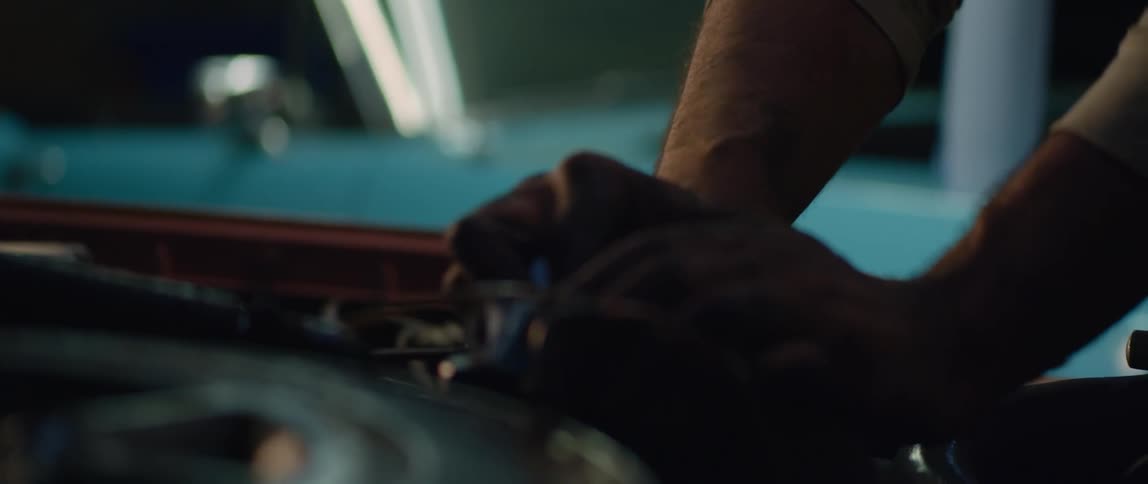Mechanic cleans a part of the engine of a car with a rag