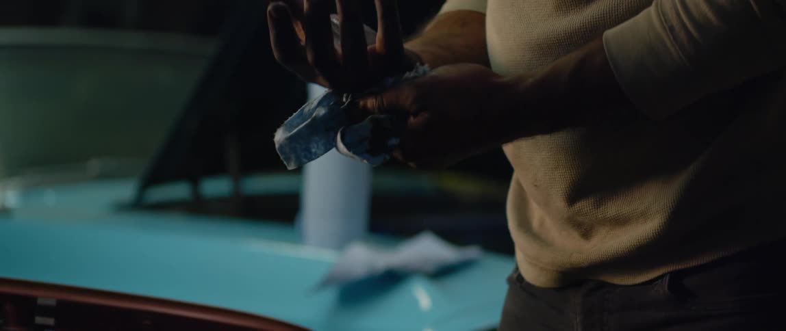 A man wipes his hands as he works on car engine
