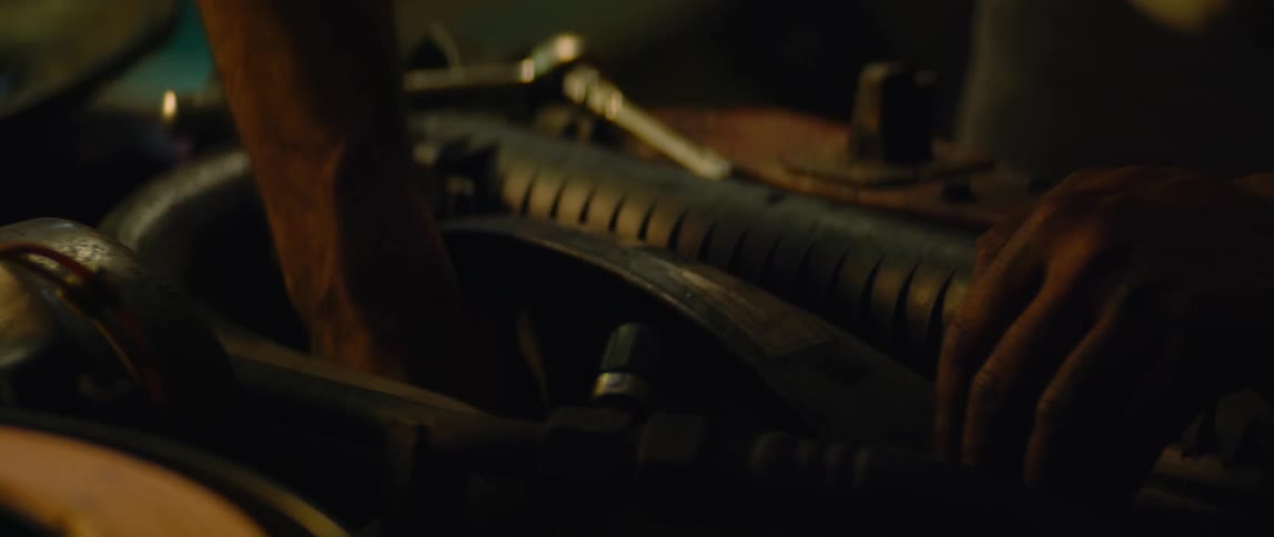 A person using tools on a cars engine