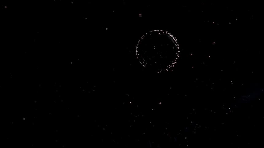 A ring of star like lights in the darkness explodes into space