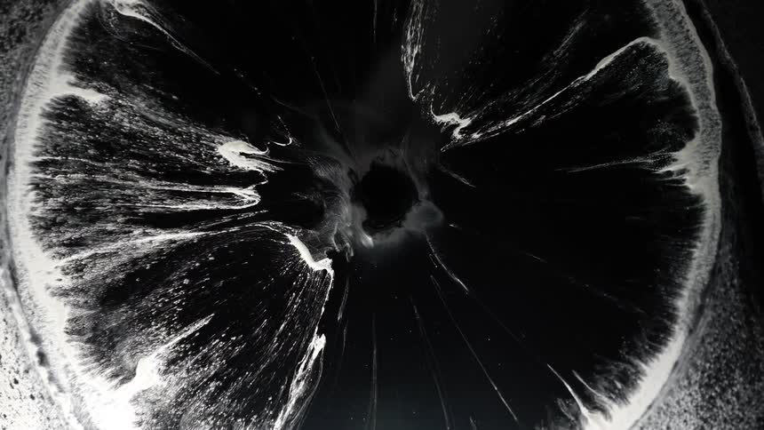 A drop falls into a gray liquid area and as the ring spreads it all turns black