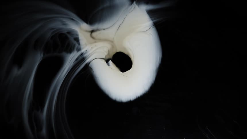 A white fluid blends into a black fluid and the patterns swirl together