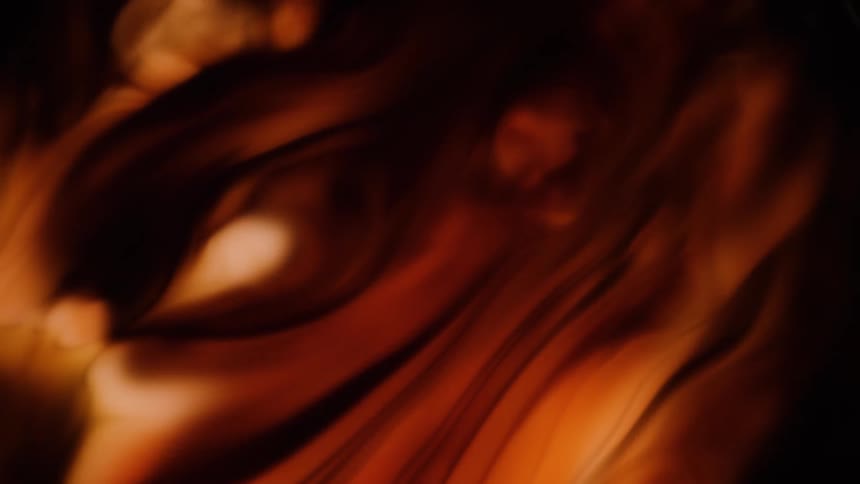 Ribbons of yellow and orange swirling with dark smoke and light