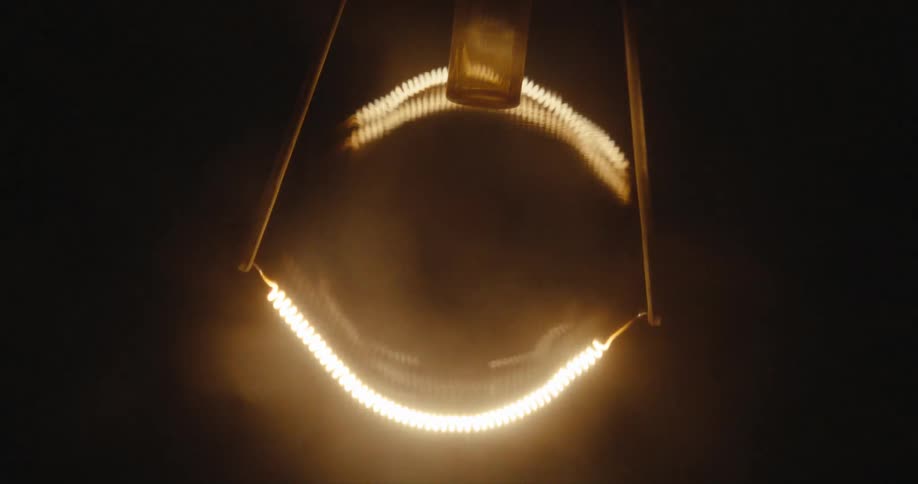 Coils on a light bulb glow and dim as light turns on and off