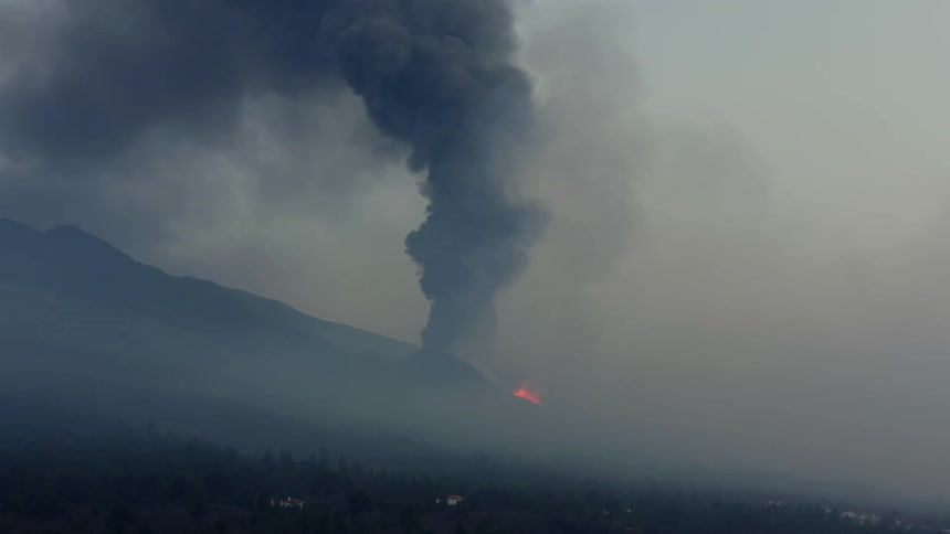 Black smoke rises from the burning flames on the side of the mountain