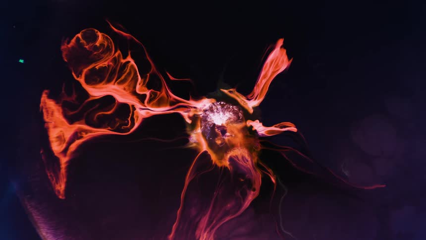 A glowing red substance expands as it grows in the darkness