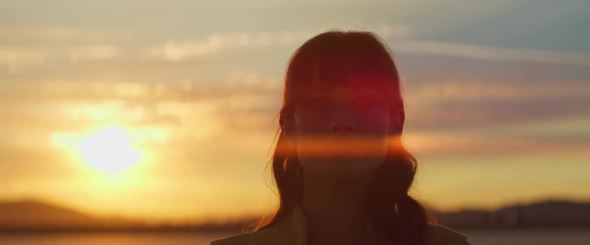 Woman stands next to a lake at dusk
