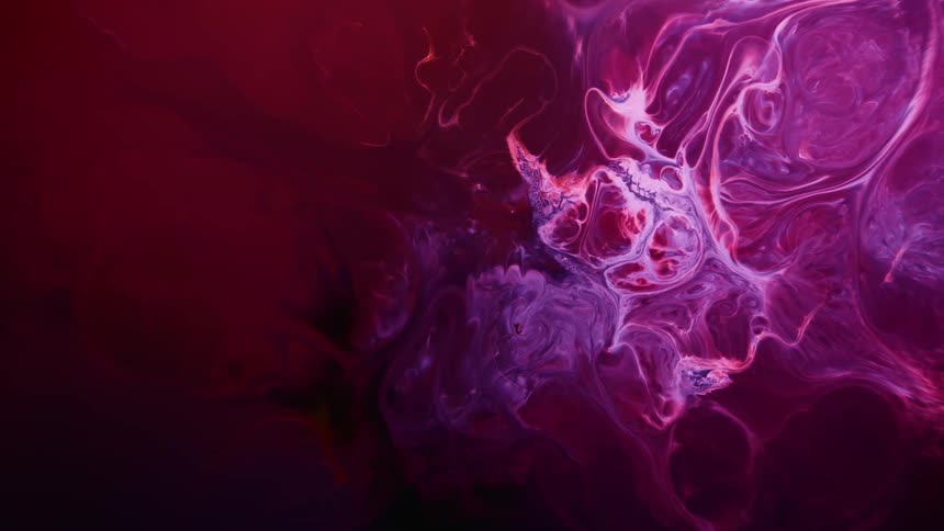 Swirls and wisps of dye floating and moving on a red background