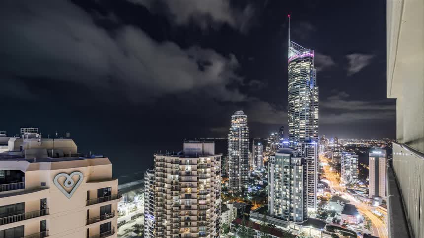 Clouds pass over the skyscrapers in a metropolis on the coast at night