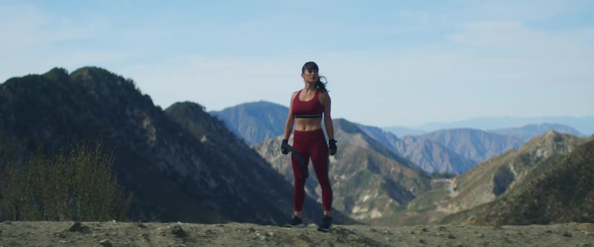 A woman is standing outdoors in a mountainous landscape