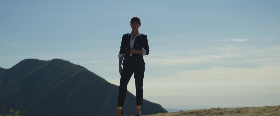A woman is dressed up and standing outside on a mountain