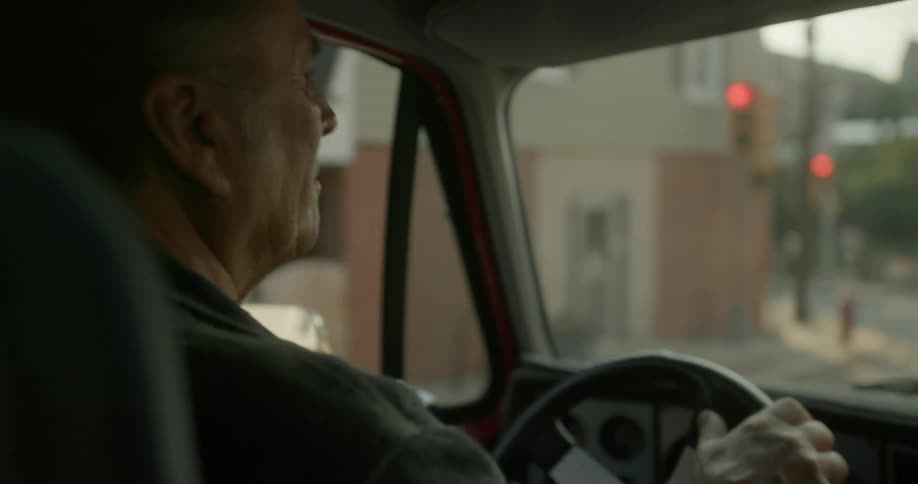 A man is driving an automobile on road through town