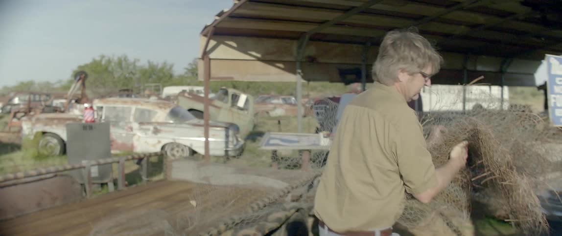 A man moving a bundle of chicken wire