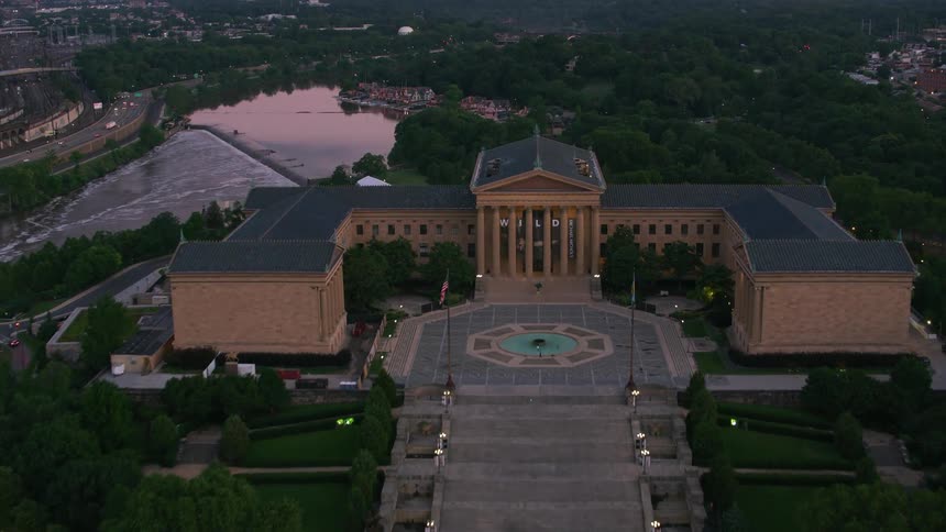 A river runs past a government building with a sprawling lawn and monuments