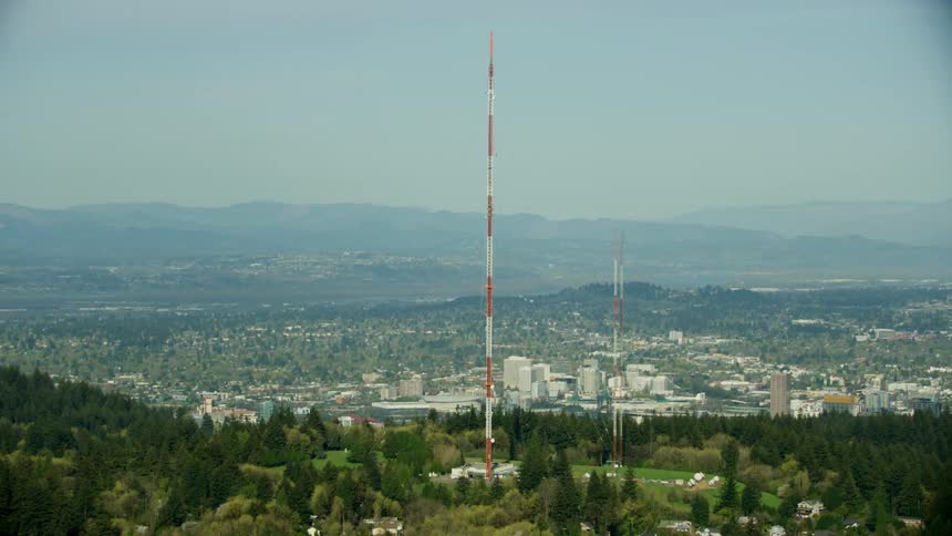 A towering radio communications antenna rises high above Portland Oregon in this sweeping aerial revealing the city landscape