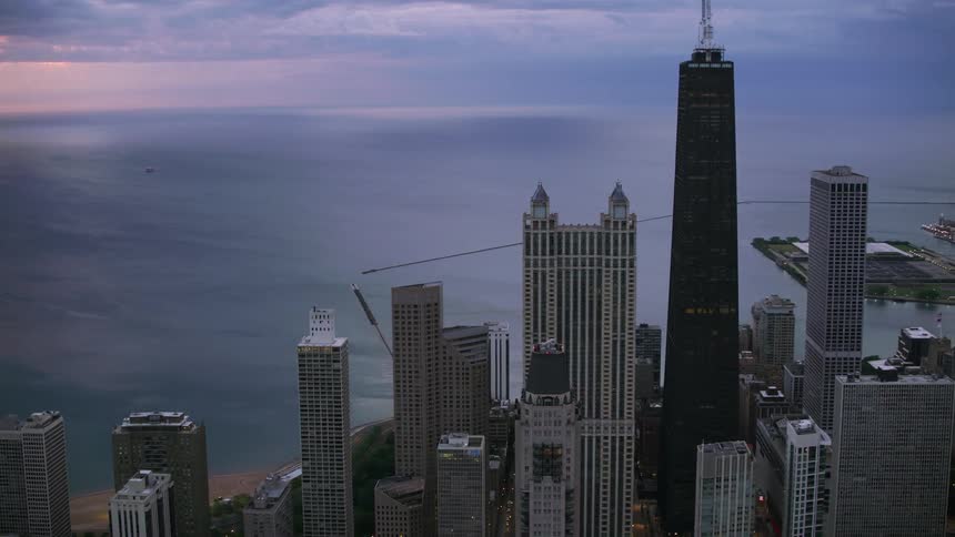 Tall buildings and skyscrapers overlook a big city coastline and harbor under a cloudy sky