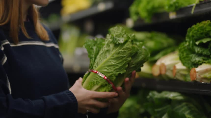 A woman is looking at lettuce in the store