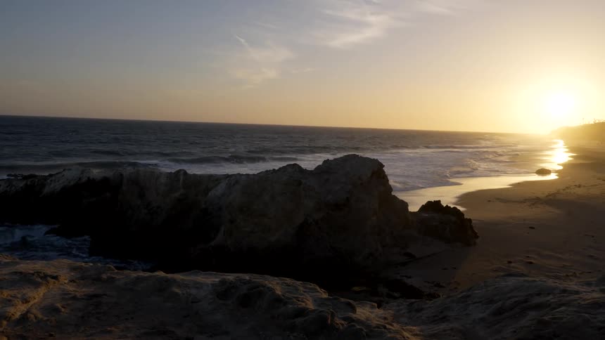 The sun shines on the horizon was waves roll over the beach