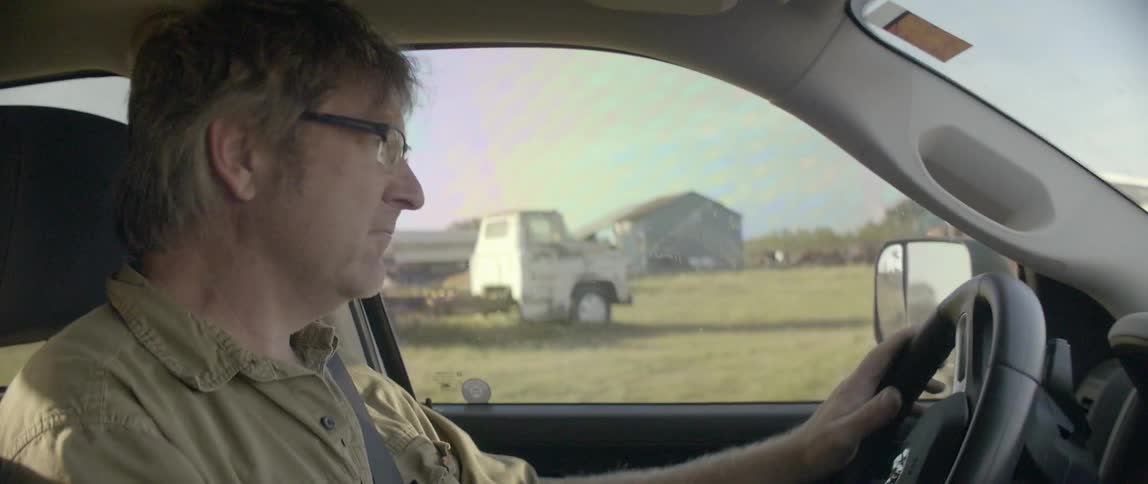 A man is driving past a farm