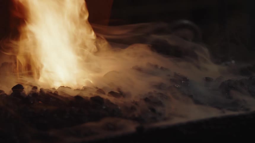 Tall flames and smoke rise from a kiln