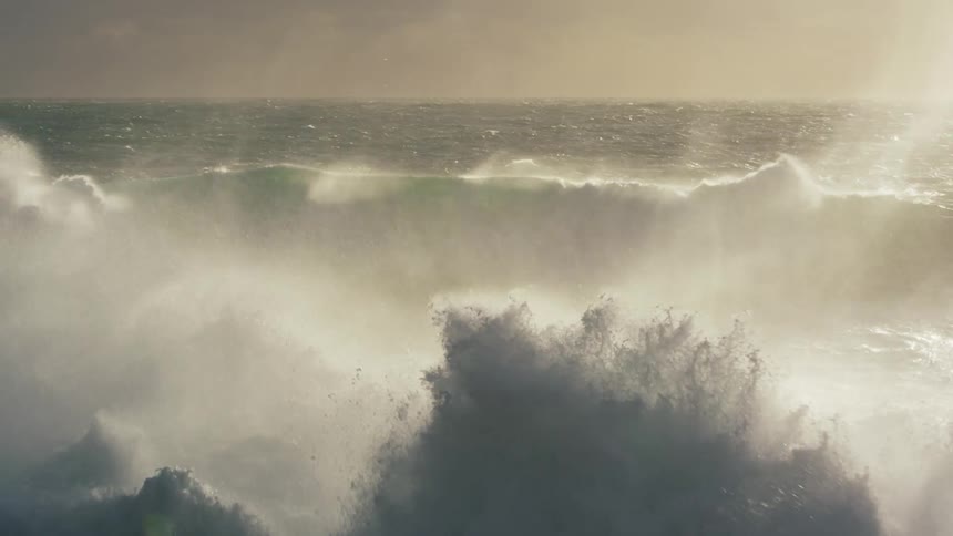 Large choppy waves are hitting the rocks on the beach violently during a storm