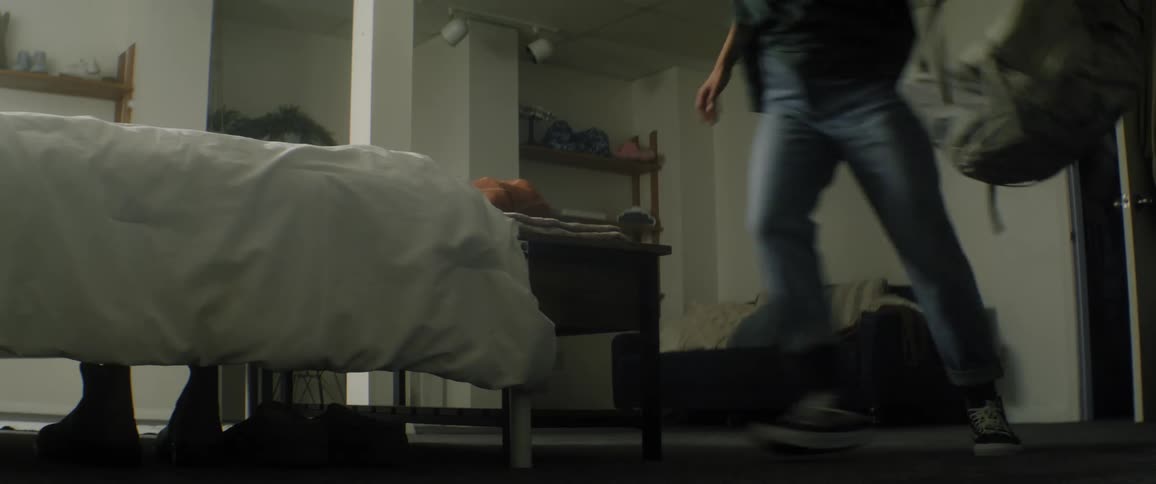 Young woman enters a bedroom then drops her backpack on the floor and flops onto the bed