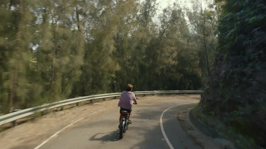 Person with pink shirt rides bike on forest road