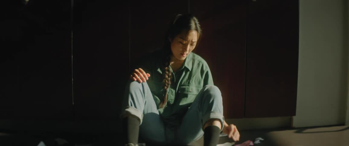 Female student sits on floor surrounded by torn paper