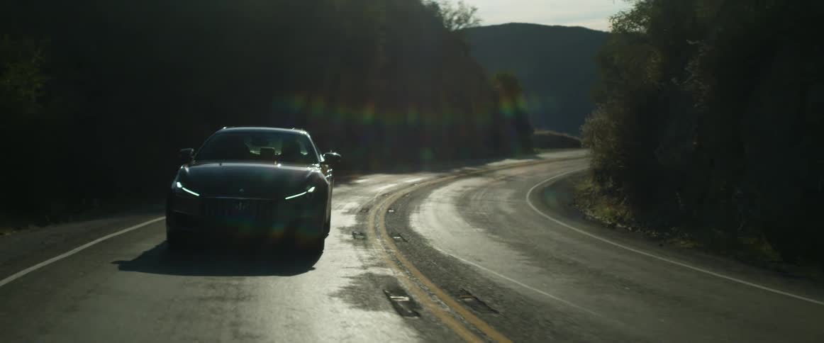 A car is driving on a road in a rural area
