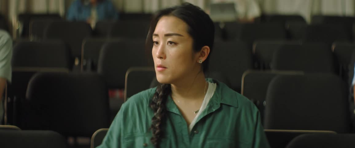 A teenage girl sits in a lecture hall and looks around upset after reading a note