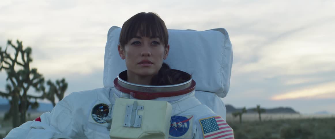 Female astronaut with space suit looks into space in the field