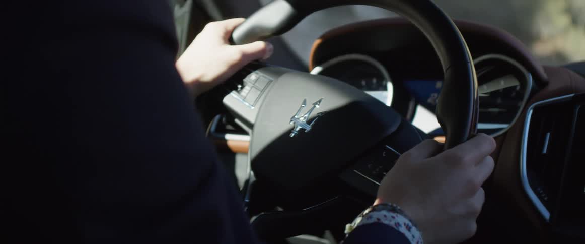 A man turning the steering wheel while driving a car