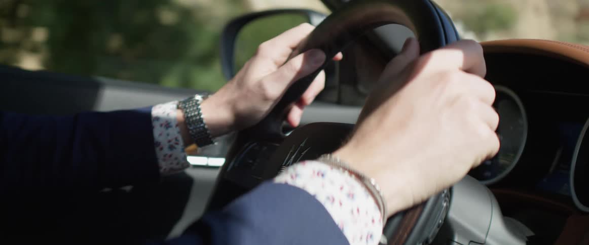A persons hands on a steering wheel