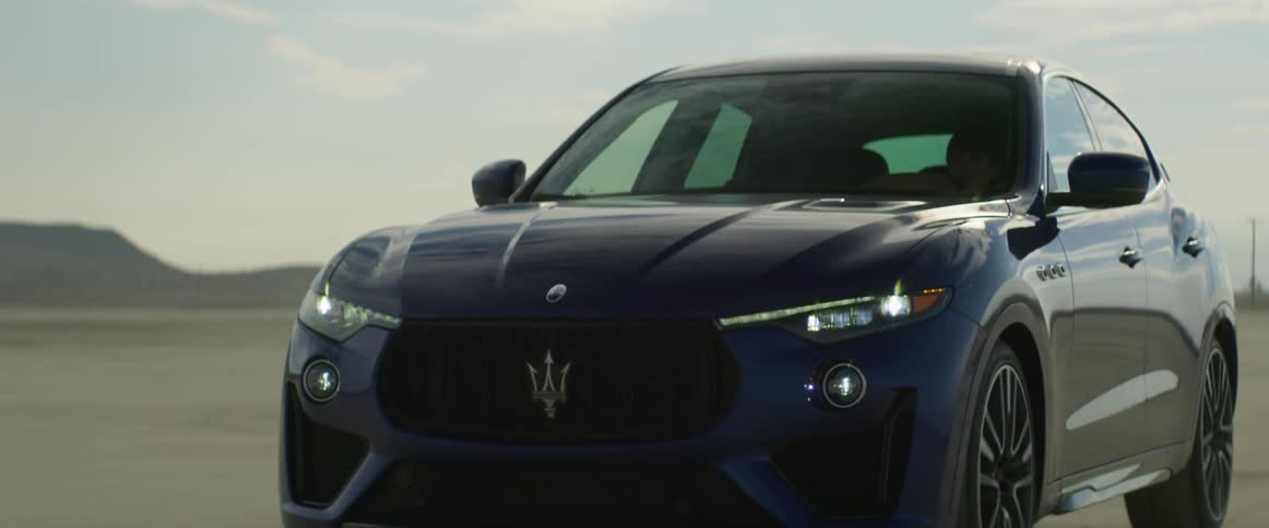 A luxury car being driving in a desert in the daytime