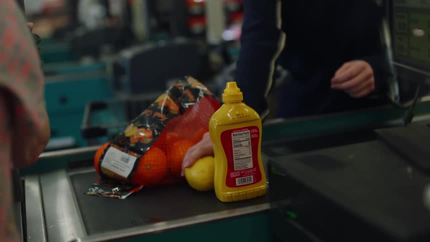 Woman places items on checkout as cashier picks them up to scan them