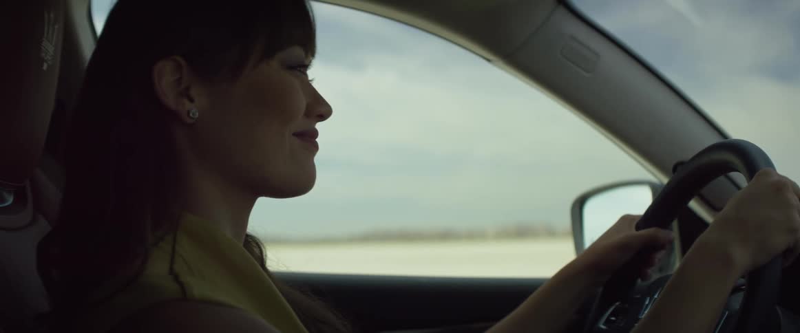 A woman smiling while driving a car in the daytime