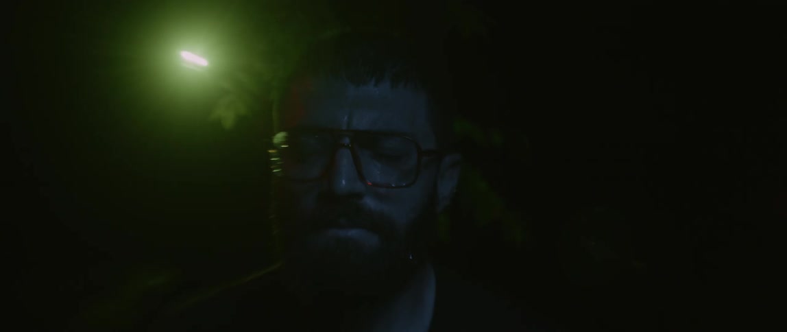 Man wearing glasses with his eyes closed as red and white lights flash around him