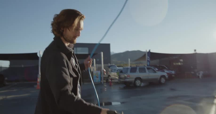 A man pressure washes his car at a selfservice car wash