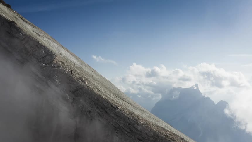 A mountaineer climbs a steep mountain slope on a clear day