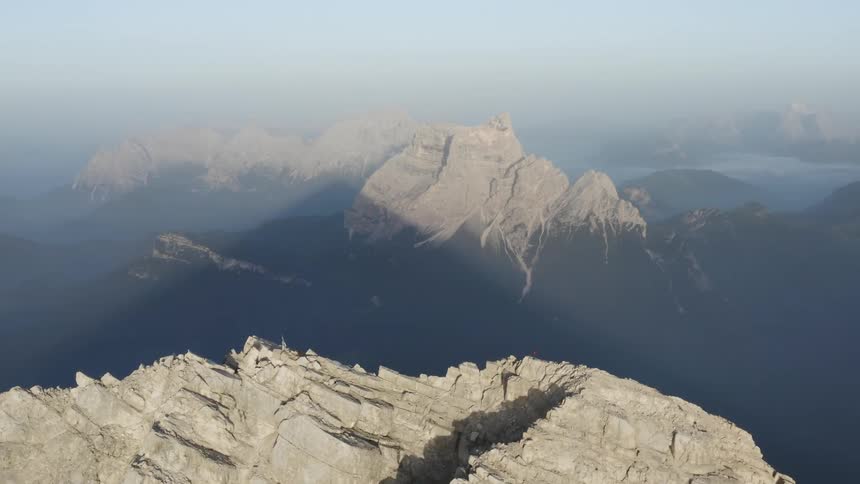 Rocky mountains are high in a foggy sky and there is a mountain ridge in the distance