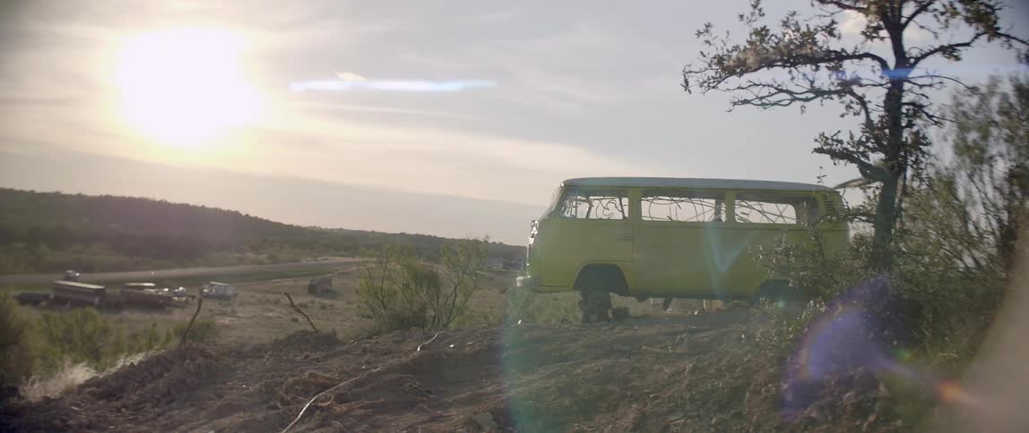 An old vw van is up on blocks in a desert setting