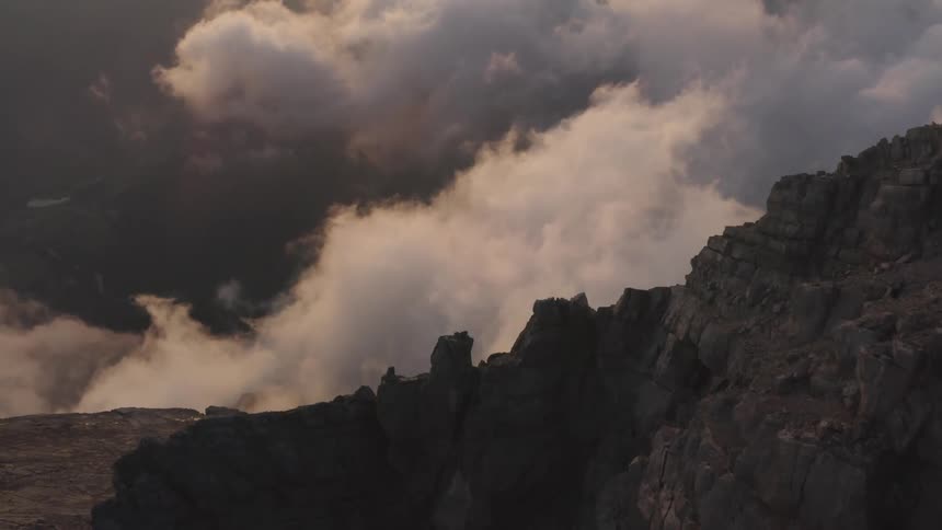 Dense clouds form over a steep and wide canyon