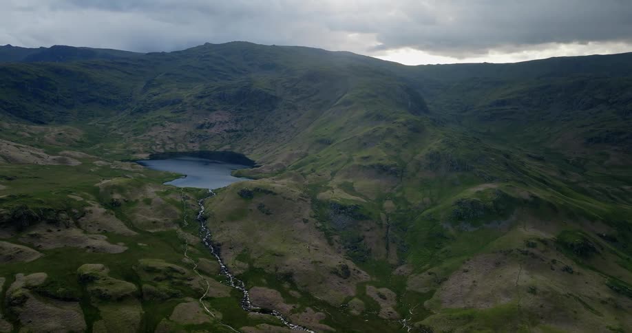 A stream of water from a blue mountain lake shimmers as it snakes down a rocky slope