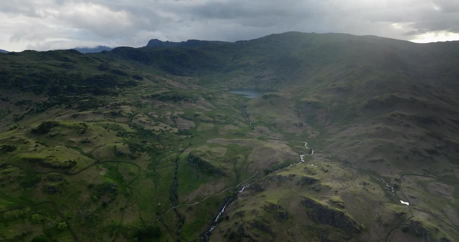 An aerial view of a river run through hills to a lake