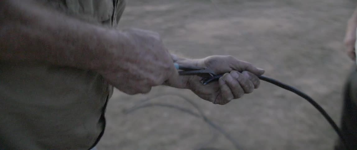 A man is cutting some wires in his hand