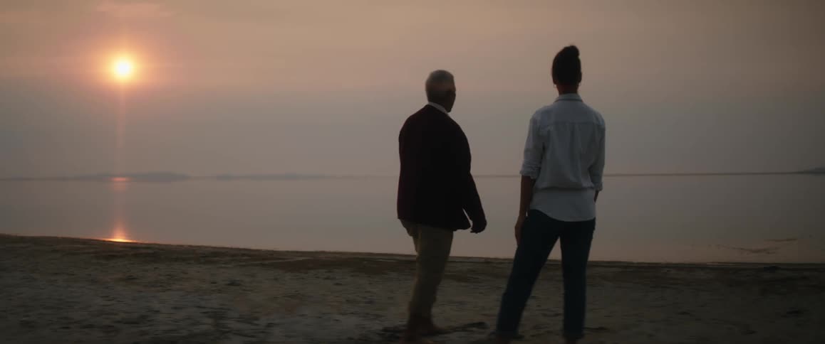 A woman helps get her blind grandfather into the right spot so he can skip stones on the water