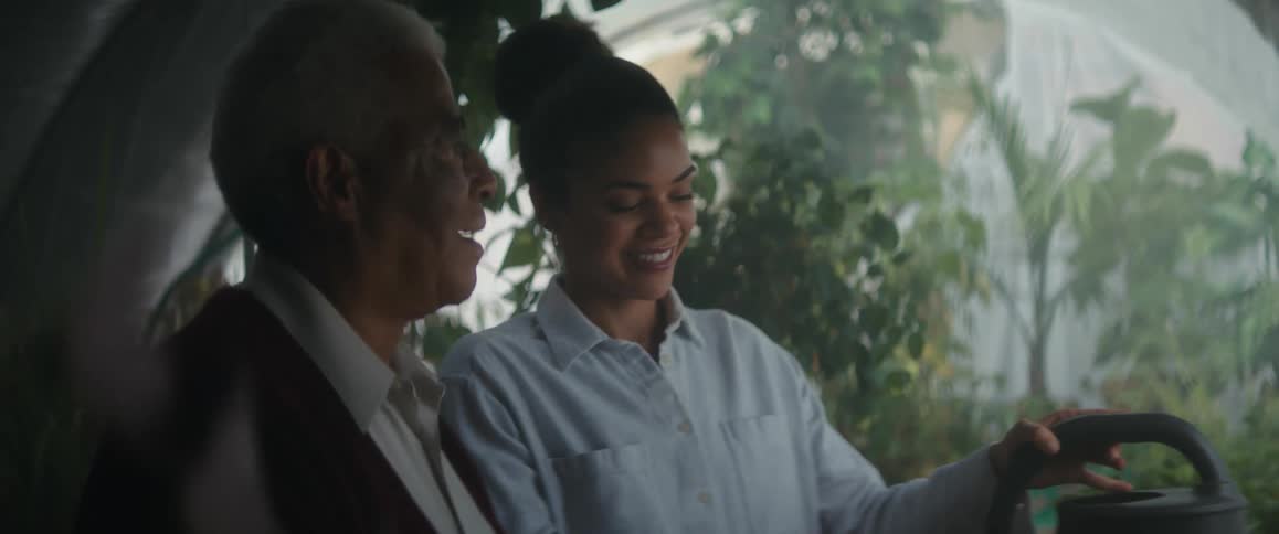Father and daughter watering plants inside a greenhouse
