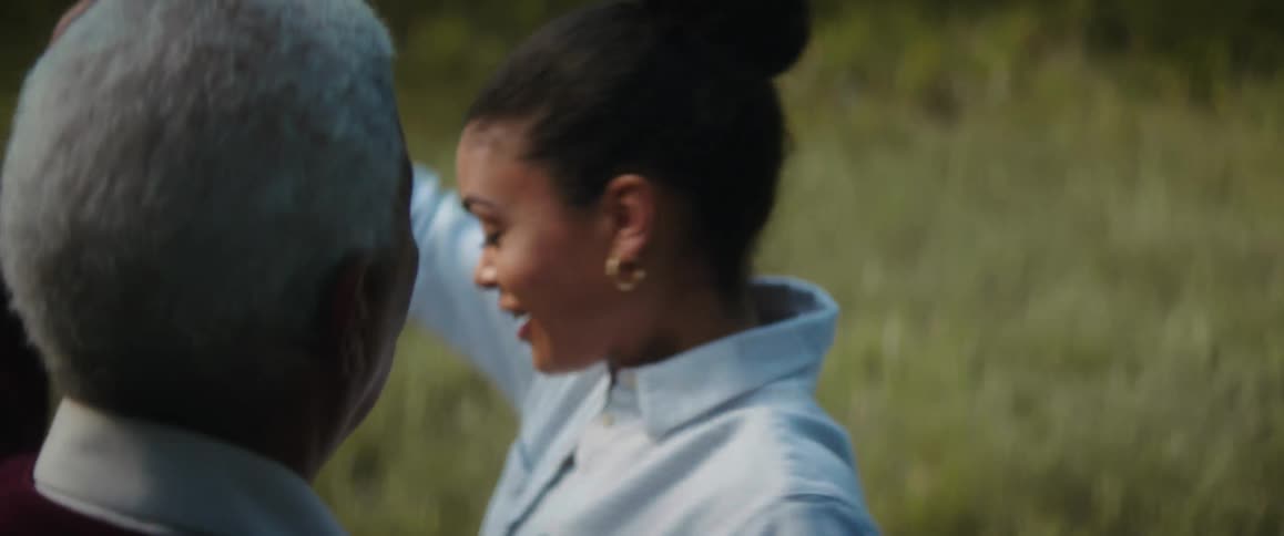 A woman dances with her father in a field