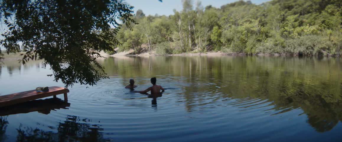 Father and daughter swimming on a lake near a small wooden pier